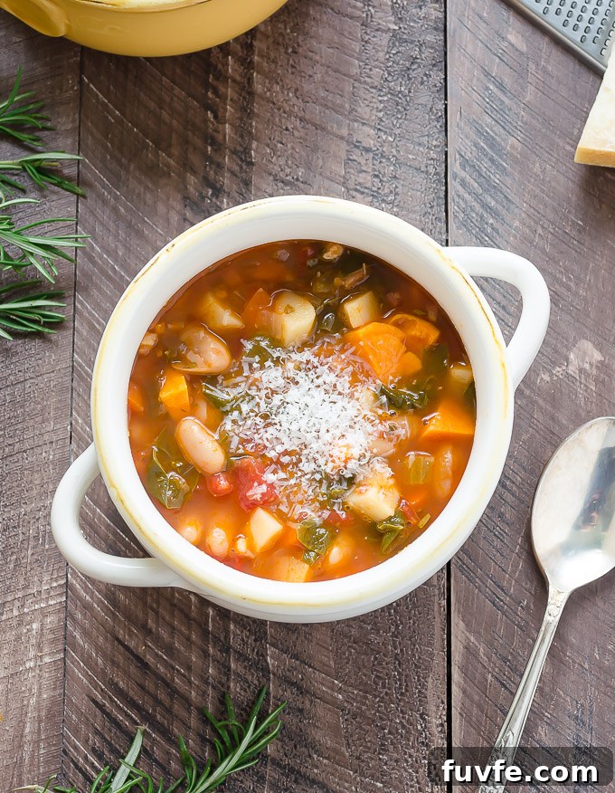 Bowl of minestrone soup in a white bowl with parmesan cheese on top