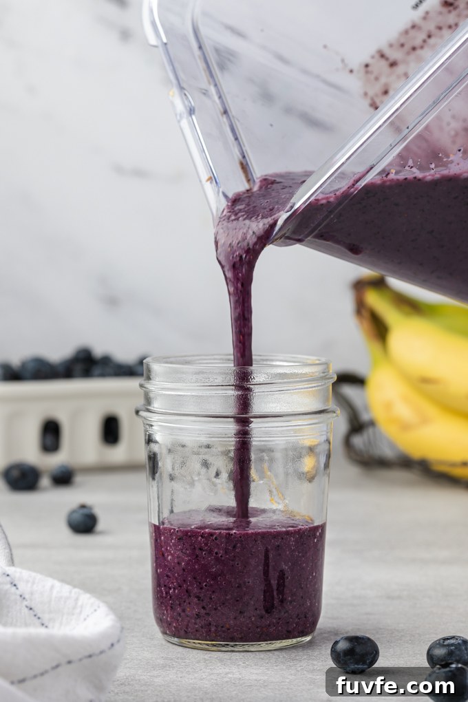 Creamy Blueberry Banana Smoothie Recipe 6 Pouring blueberry banana smoothie into a jar