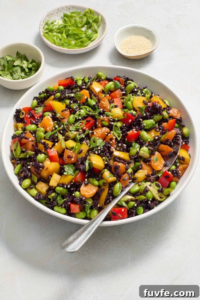 Asian black rice salad in a bowl with a serving spoon.