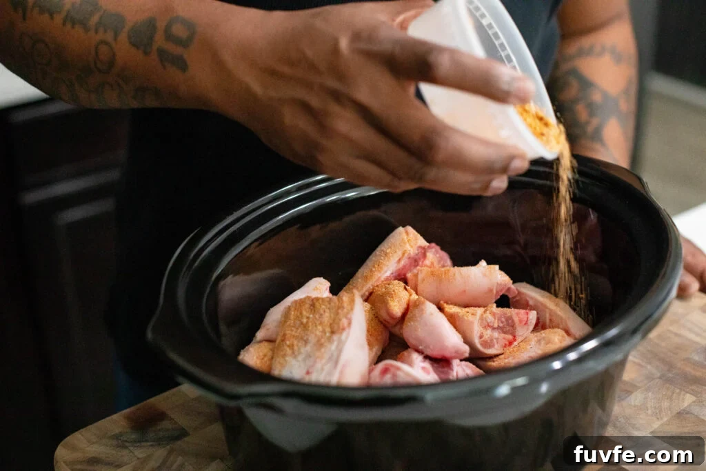 Pigs Feet in a crockpot being seasoned with spices.