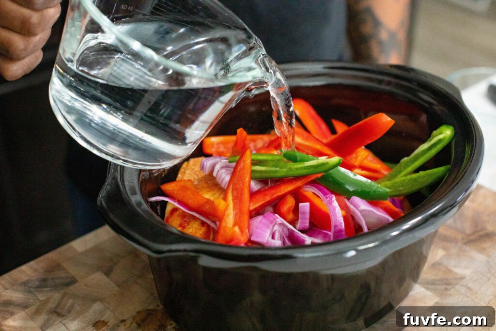 Pouring in 4 cups of water into crockpot with Pigs Feet, sliced vegetables, and spices.