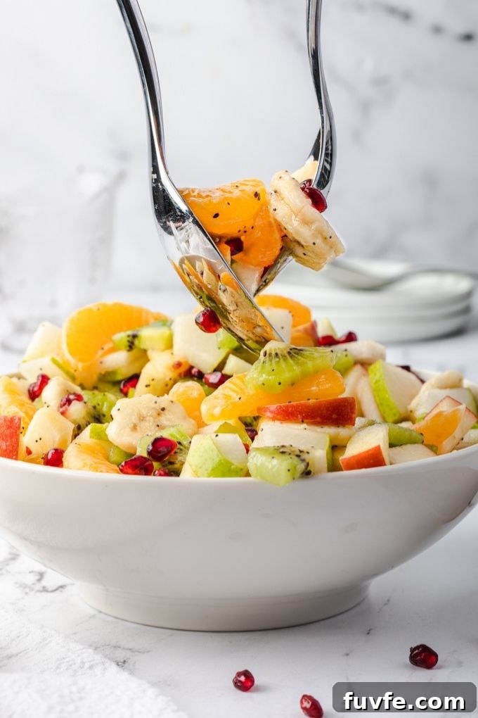 Winter Citrus and Pomegranate Fruit Salad 3 Serving spoons tossing winter fruit salad over a white bowl