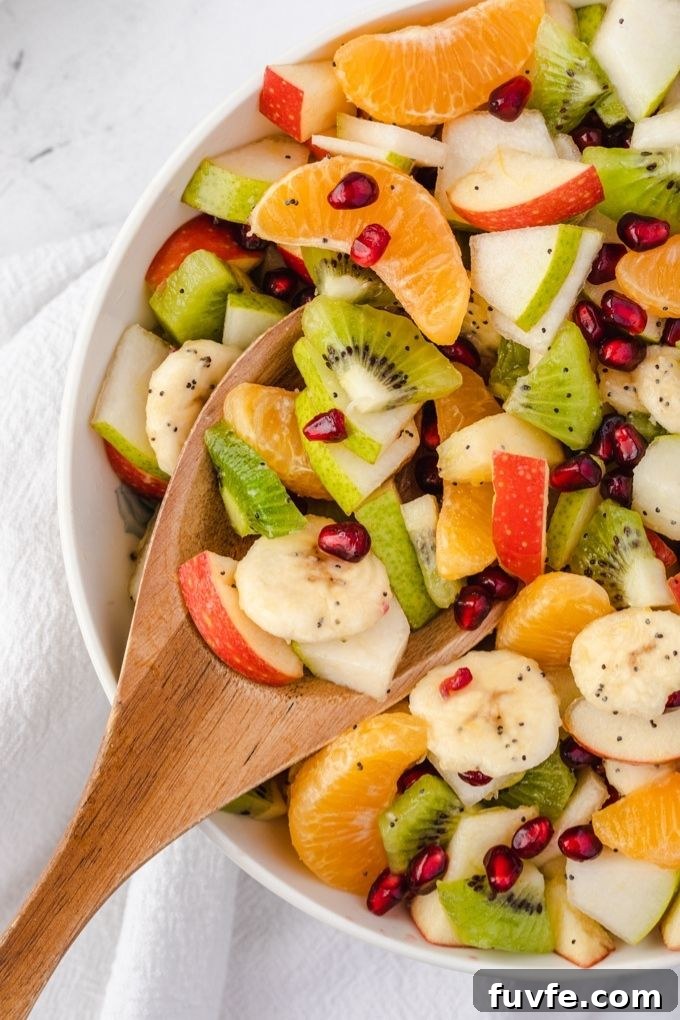 Winter Citrus and Pomegranate Fruit Salad 6 Wooden spoon digging into a bowl of winter fruit salad