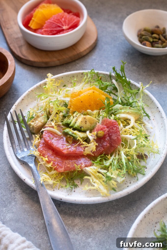 Citrus Frisee Salad with Fennel and Avocado 8 Frisee salad with citrus on a plate topped with avocado and pistachios.