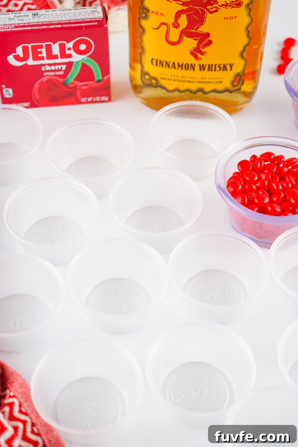 Clear jello shot cups with some fireball jello shot ingredients in the background.