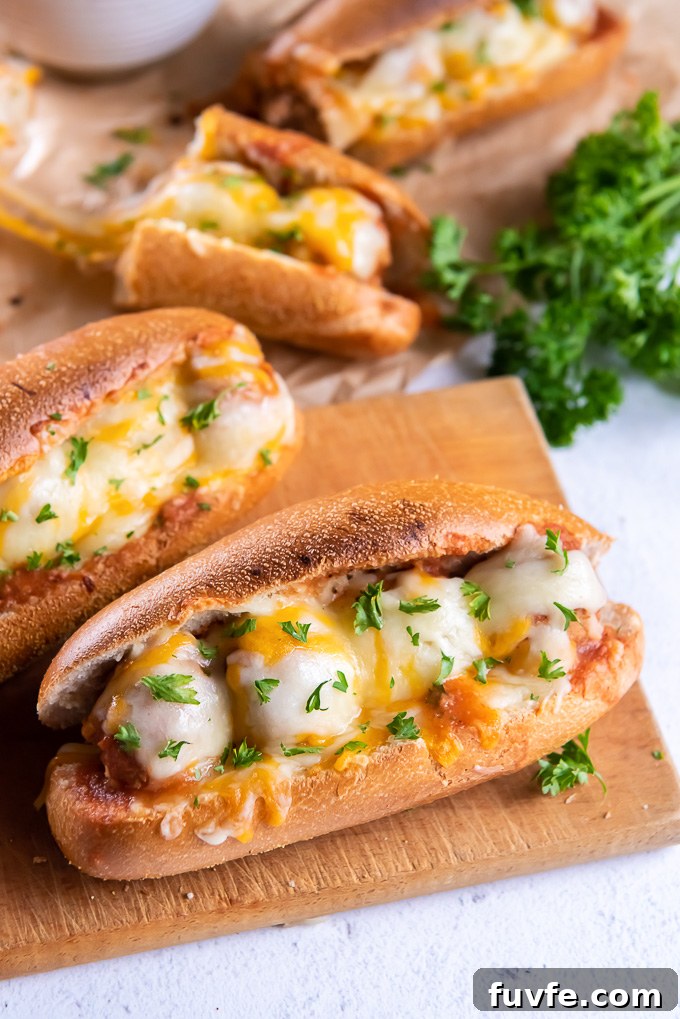 Slow Cooker BBQ Meatball Subs Recipe 3 Meatball subs on cutting board with fresh parsley