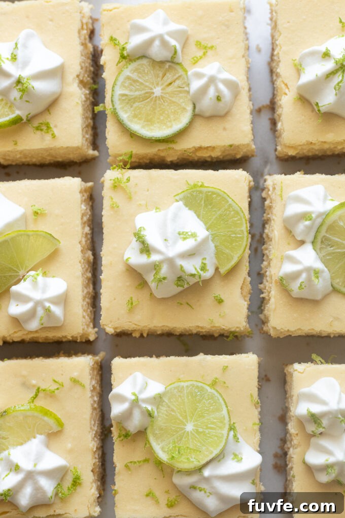 Cheesecake bars cut into squares with whipped cream, key lime zest and juice.