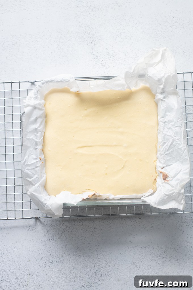 Baked cheesecake bars cooling on wire rack.