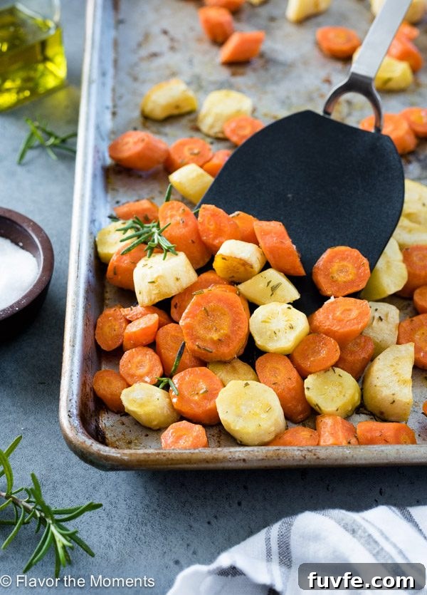Roasted carrots and parsnips on baking sheet with spatula