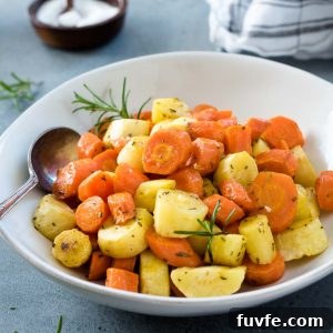 Roasted carrots and parsnips in a white bowl with spoon